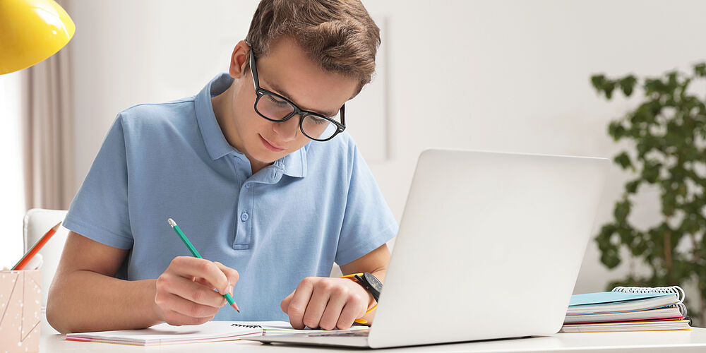 Junge schreibt am Laptop Bewerbung